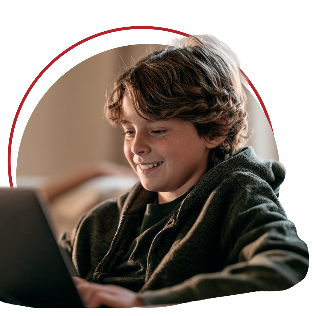 A smiling boy talking with his therapist on a laptop at home