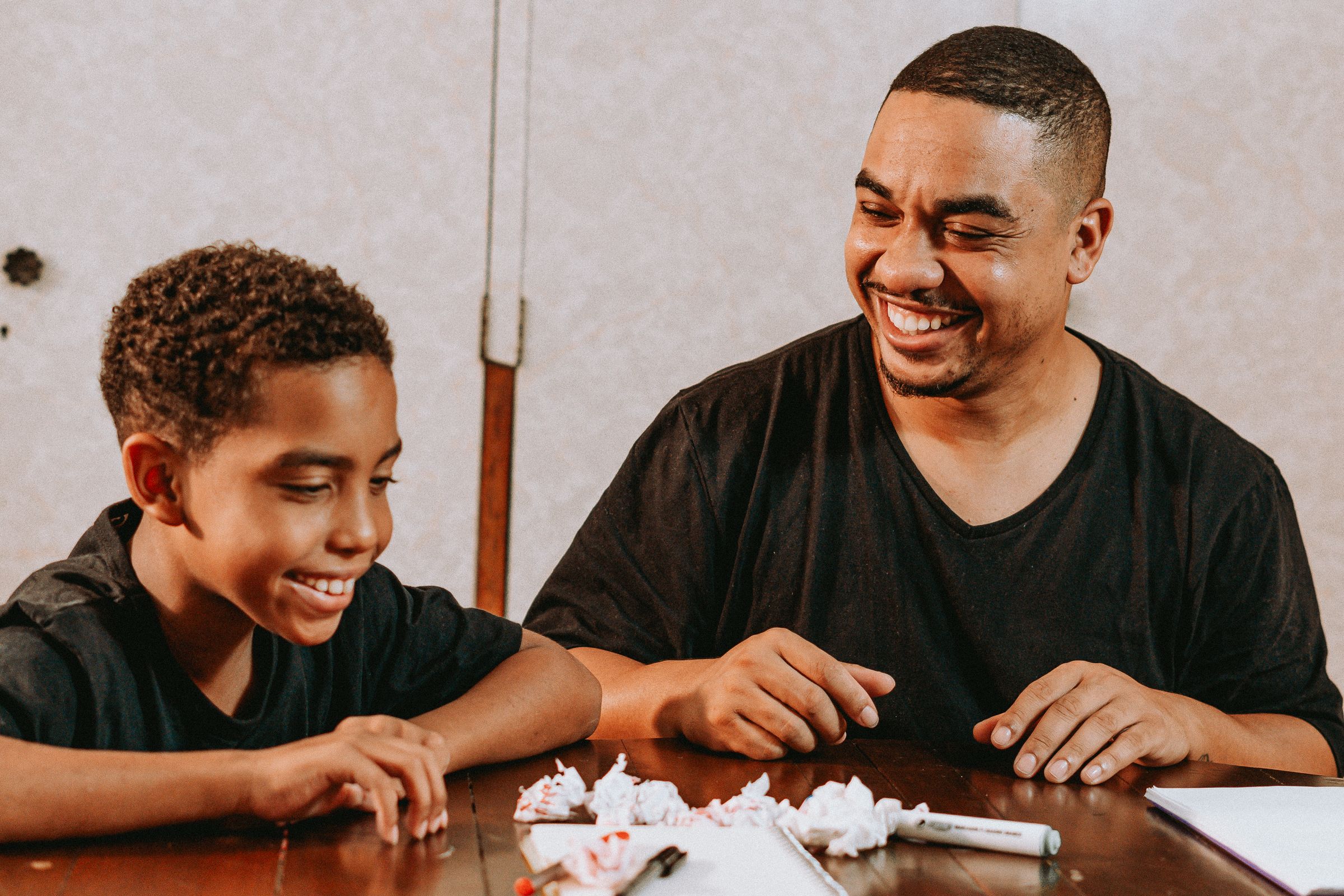 A boy and his father laughing together while working on an activity