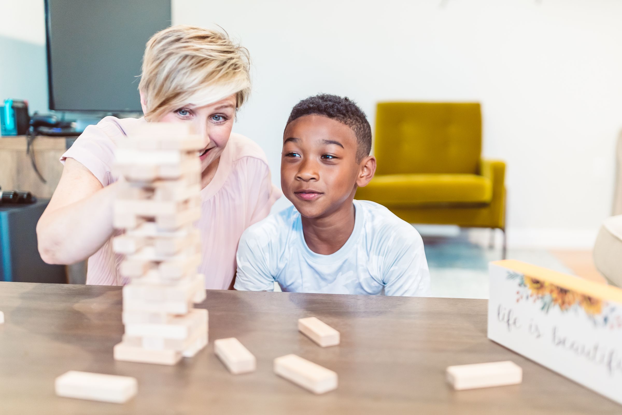 A care worker playing a game with a boy at a table