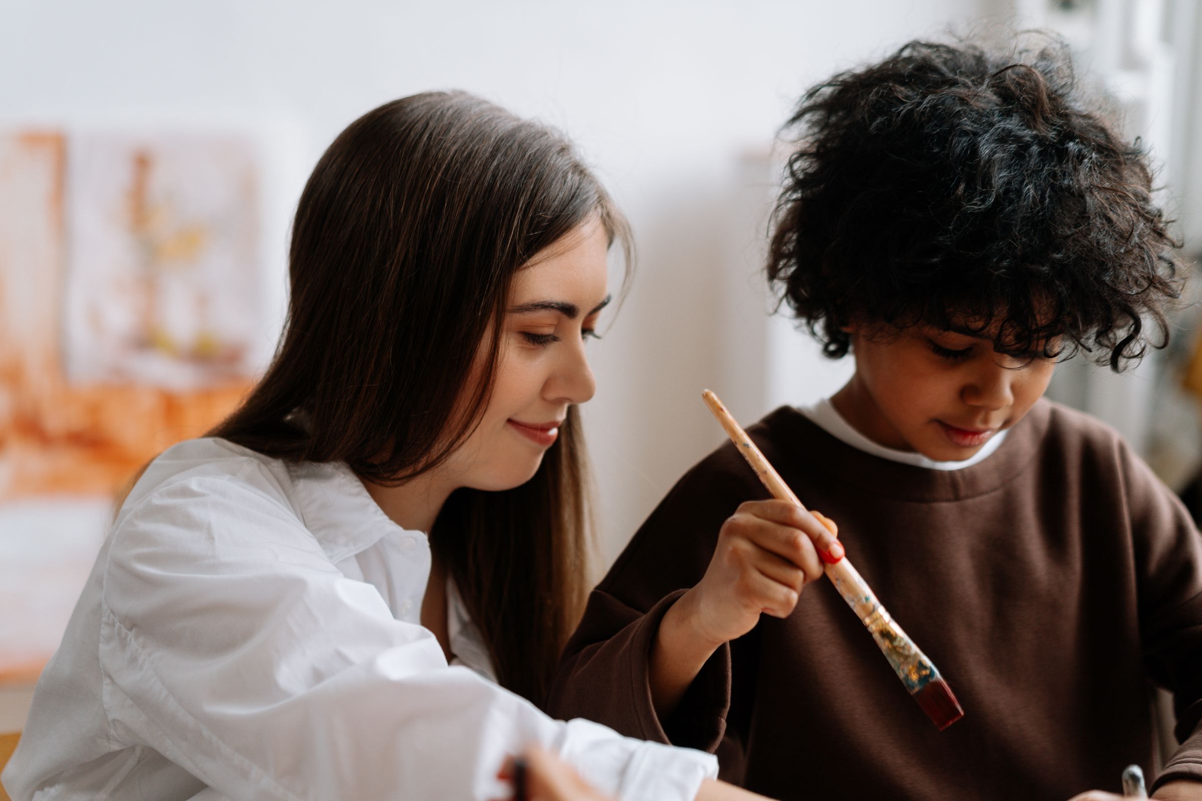 A young peer support worker painting with a boy