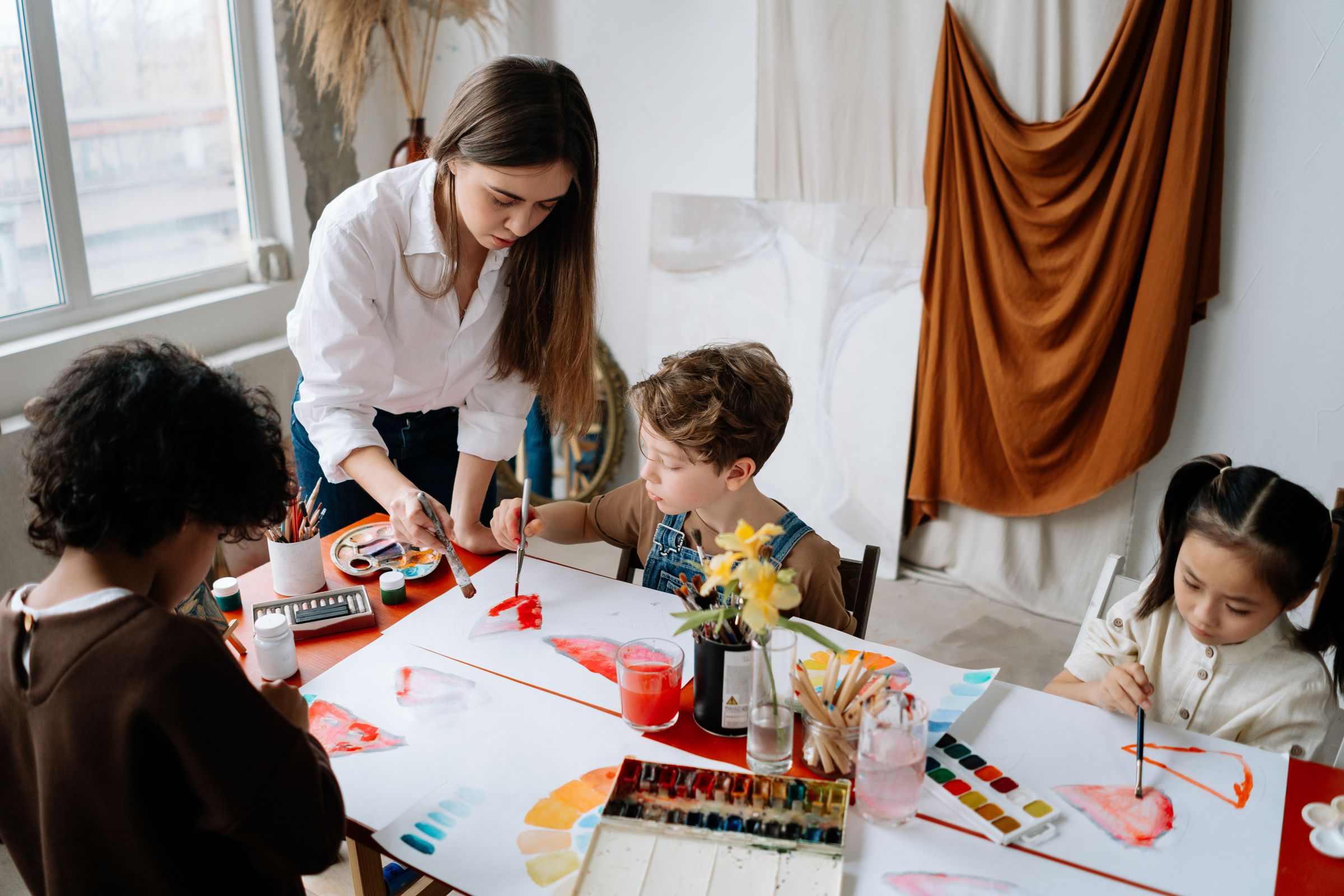A young peer specialist painting with children at a table